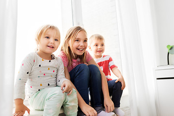 Image showing happy little kids sitting on window sill