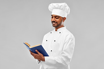 Image showing happy male indian chef reading cookbook