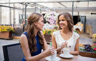 Image showing smiling young women drinking coffee at street cafe