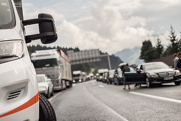 Image showing Typical scene on European highways during summer holiadays rush hour. A traffic jam with rows of cars tue to highway car accident. Empty emergency lane. Shallow depth of field