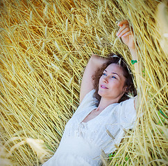 Image showing beautiful woman lies among the ears of corn in the field