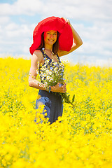 Image showing beautiful white woman in a red hat and with a bouquet of wildflo