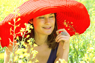 Image showing pretty woman in a red hat in the field, among the flowers