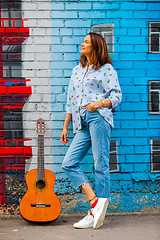 Image showing Beautiful brunette in blue jeans with a guitar