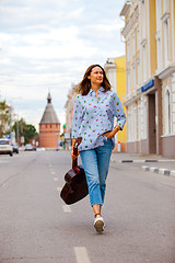 Image showing woman with a guitar smiles and goes along the road