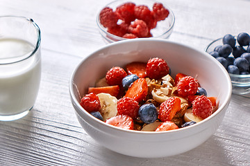 Image showing Natural organic raspberry, strawberry, blueberry, nuts, oat flakes and soy milk - the set of ingredients for healthy breakfast on a wooden background
