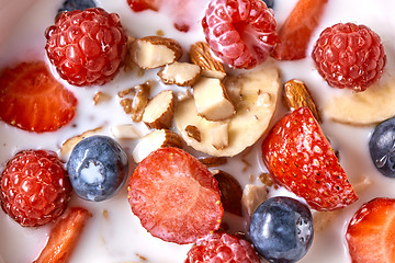 Image showing Close up of natural fresh ingredients with healthy breakfast - strawberry, blueberry, chopped almonds, granola and fresh milk. Top view.