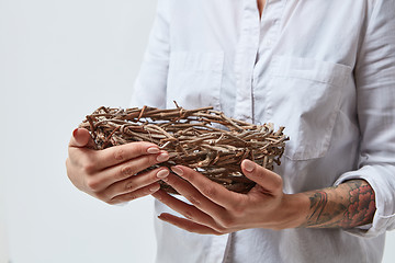 Image showing The girl is holding a nest of branches in her hands,