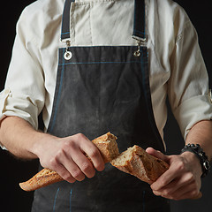 Image showing Male hands break the baguette