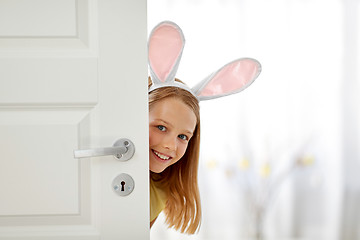 Image showing happy girl with easter bunny ears peeking out door