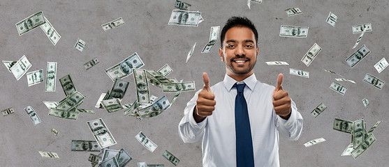 Image showing indian businessman showing thumbs up over money