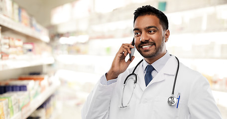 Image showing smiling indian male doctor calling on smartphone