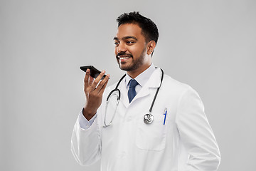 Image showing smiling indian male doctor calling on smartphone