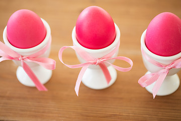 Image showing pink colored easter eggs in holders on table