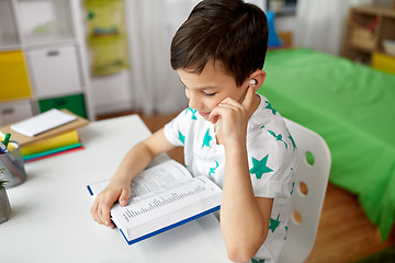 Image showing student boy in earphones reading book at home