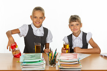 Image showing Two school girlfriends drink juice and eat cookies at a table in a school class