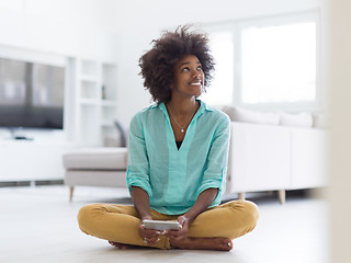 Image showing black women using tablet computer on the floor at home