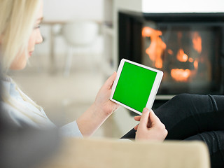 Image showing young woman using tablet computer in front of fireplace