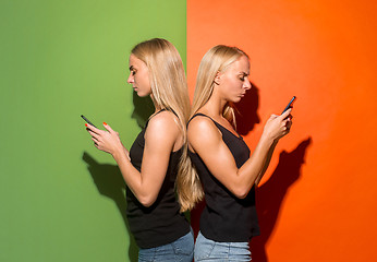 Image showing Portrait of a happy smiling casual girls with mobile phones over studio background