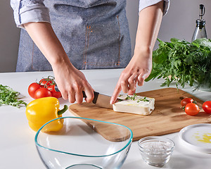 Image showing Woman\'s hands cut the cheese with the sprouts on the wooden board on the kitchen table with different vegetables. Step by step cooking healthy salad