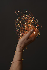 Image showing bright christmas lights in woman\'s hands