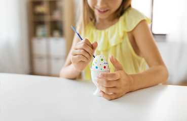 Image showing close up of girl coloring easter egg by paintbrush