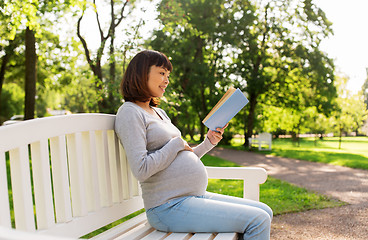 Image showing happy pregnant asian woman reading book at park