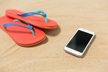 Image showing smartphone and flip flops on beach sand