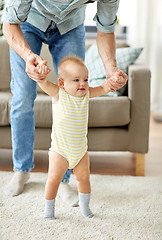 Image showing father helping baby daughter with walking at home