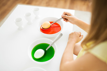 Image showing girl coloring easter eggs by liquid dye at home