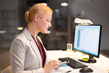 Image showing businesswoman with smartphone at night office