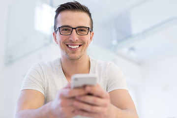 Image showing young man using a mobile phone  at home