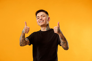 Image showing The happy businessman standing and smiling against orange background.