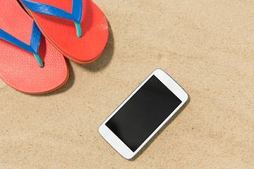 Image showing smartphone and flip flops on beach sand