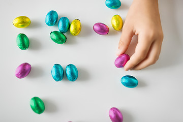 Image showing hand of child with chocolate easter eggs in foil