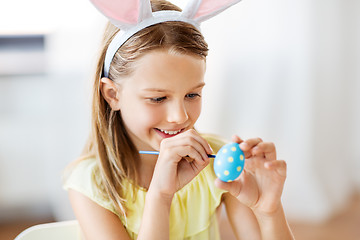 Image showing happy girl coloring easter eggs at home