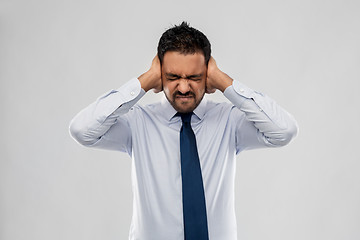 Image showing indian businessman covering ears with hands