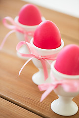 Image showing pink colored easter eggs in holders on table