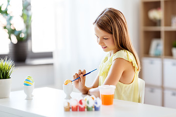 Image showing happy girl coloring easter eggs at home