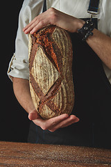 Image showing Hands of man holding oval bread