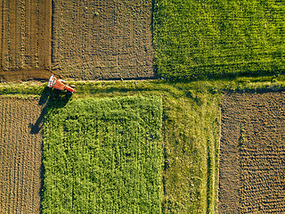 Image showing Aerial view from the drone, a bird\'s eye view of agricultural fields with a road through and a tractor on it in the spring evening at sunset