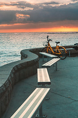 Image showing Bicycle and empty bench seats overlooking ocean at sunrise