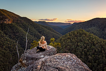 Image showing Woman on a rock with views of sunset over mountain valley gorge