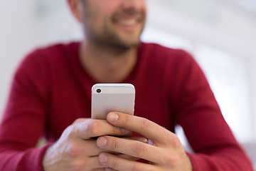 Image showing young man using a mobile phone  at home