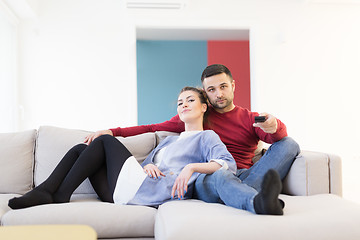 Image showing Young couple on the sofa watching television