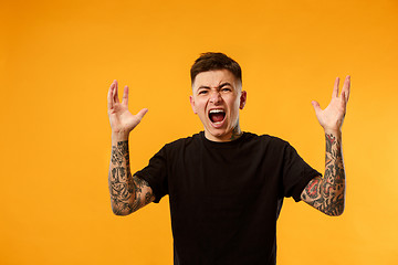 Image showing The young emotional angry man screaming on studio background