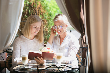 Image showing Portrait of beautiful mature mother and her daughter holding cup sitting at home