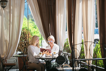 Image showing Portrait of beautiful mature mother and her daughter holding cup sitting at home