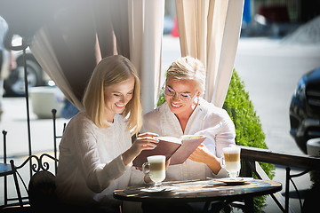 Image showing Portrait of beautiful mature mother and her daughter holding cup sitting at home