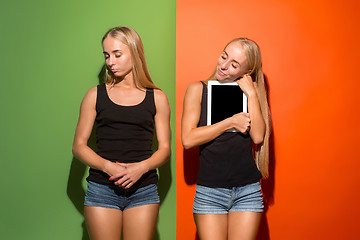 Image showing Picture of two young happy women looking at the camera and holding laptop.